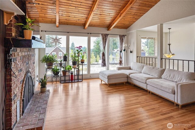 living area with a brick fireplace, light wood-type flooring, and wood ceiling
