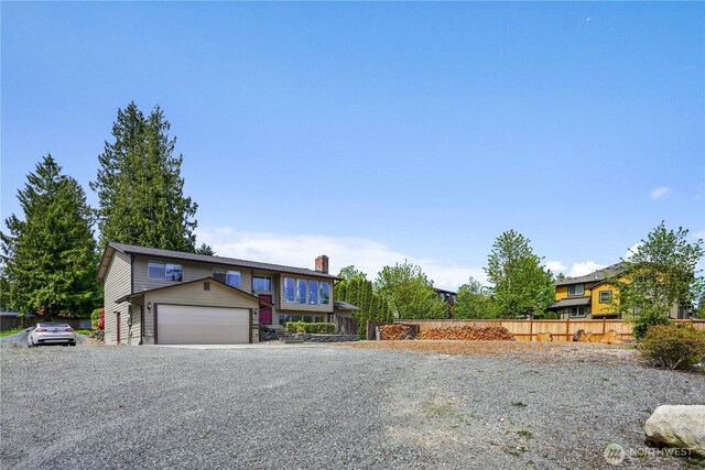 view of front facade featuring fence, a chimney, and a garage