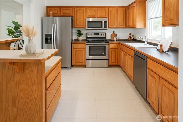kitchen with appliances with stainless steel finishes, a sink, and brown cabinetry