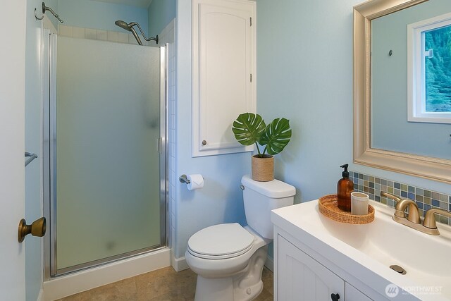 full bathroom featuring a shower stall, toilet, backsplash, and vanity