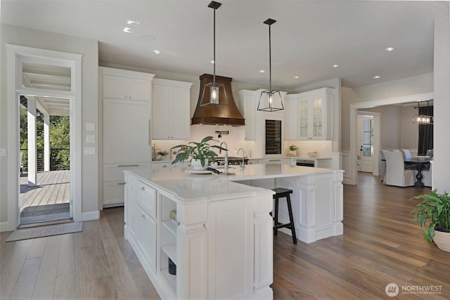 6130 Maltby Rd, Woodinville, WA 98072 - kitchen with premium range hood, dark wood-style floors, white cabinetry, light countertops, and an island with sink