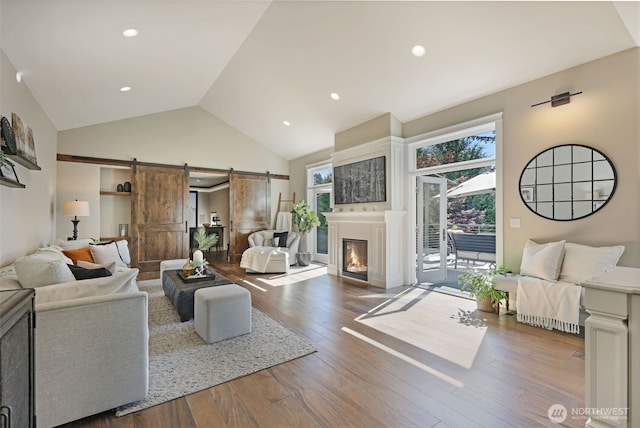 6130 Maltby Rd, Woodinville, WA 98072 - living area with a barn door, wood finished floors, high vaulted ceiling, a glass covered fireplace, and recessed lighting