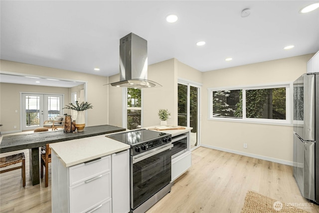 9919 Arrowsmith Ave S, Seattle, WA 98118 - kitchen featuring appliances with stainless steel finishes, island exhaust hood, white cabinetry, baseboards, and light wood-style floors