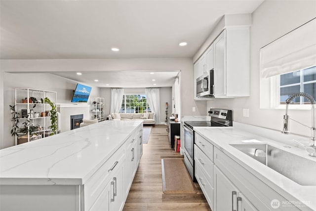 3342 Greenwood Ave W, University Place, WA 98466 - kitchen featuring appliances with stainless steel finishes, a sink, light wood finished floors, open floor plan, and a center island