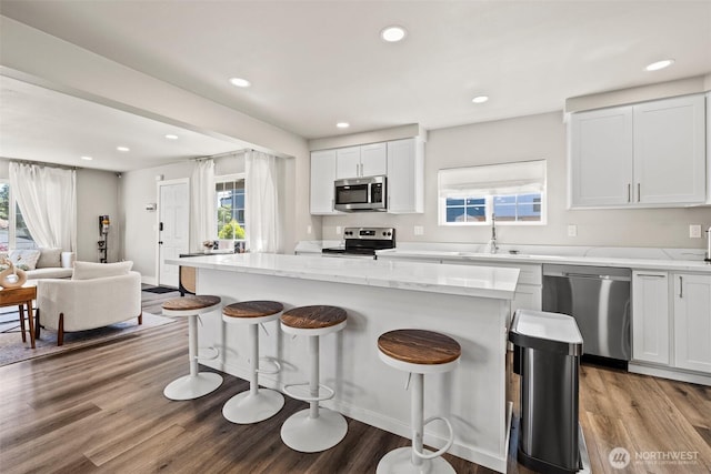 3342 Greenwood Ave W, University Place, WA 98466 - kitchen featuring appliances with stainless steel finishes, a sink, a kitchen bar, wood finished floors, and a center island