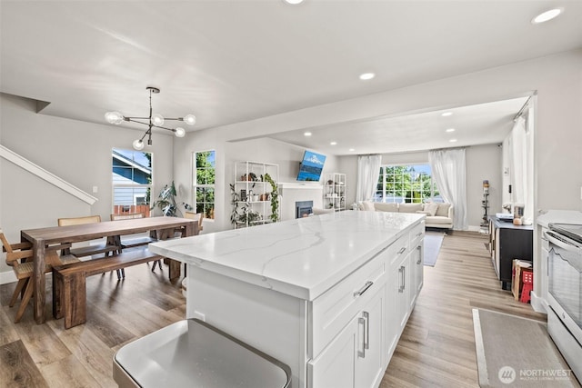3342 Greenwood Ave W, University Place, WA 98466 - kitchen featuring open floor plan, white cabinets, a center island, a fireplace, and light wood-style flooring
