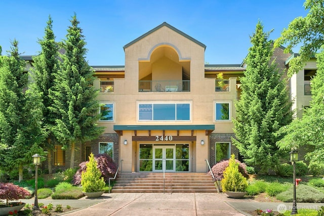2440 S Steele St Unit 101, Tacoma, WA 98405 - view of front of home with a balcony, brick siding, stucco siding, and french doors