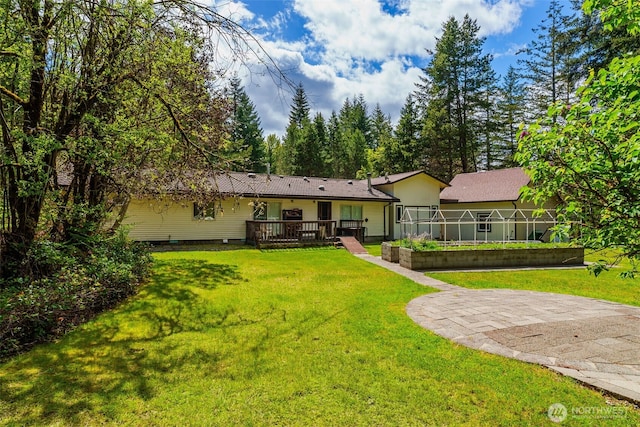 rear view of house with a wooden deck and a yard