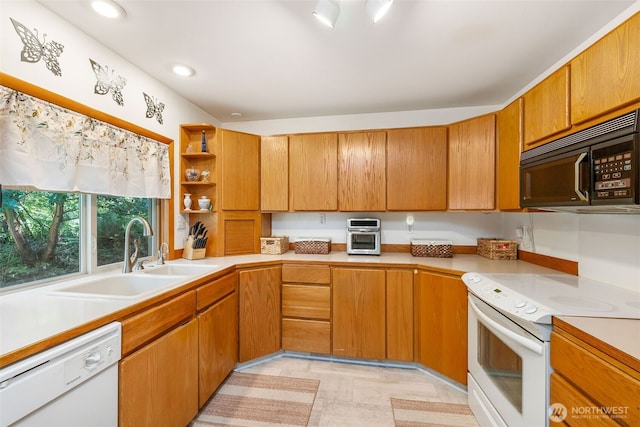 kitchen featuring white appliances, a sink, open shelves, light countertops, and brown cabinetry