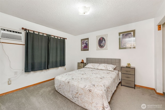 bedroom with carpet flooring, a wall mounted air conditioner, baseboards, and a textured ceiling