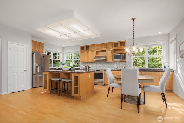 26108 SE 27th St, Sammamish, WA 98075 - kitchen with appliances with stainless steel finishes, a center island, light wood-style floors, dark countertops, and under cabinet range hood