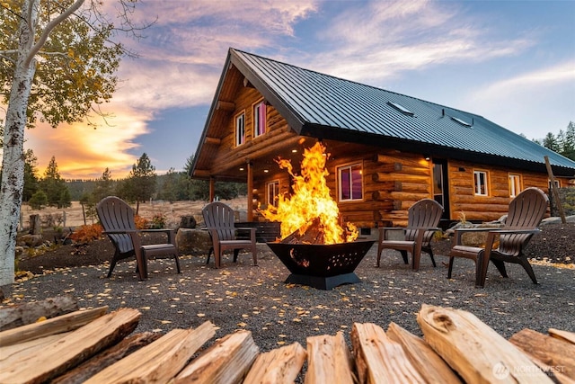 rear view of house with a fire pit, log siding, metal roof, and a standing seam roof