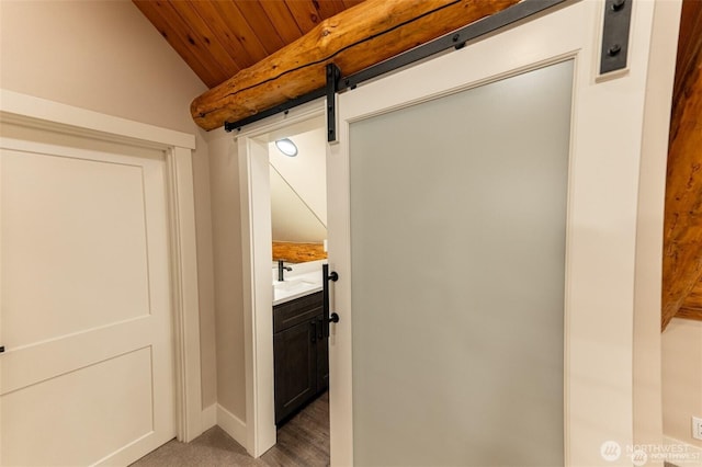 laundry area featuring a barn door, wood ceiling, and baseboards