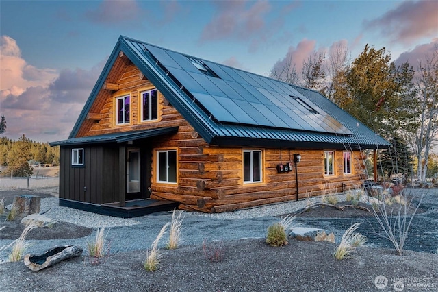 back of house featuring metal roof, log siding, and a standing seam roof
