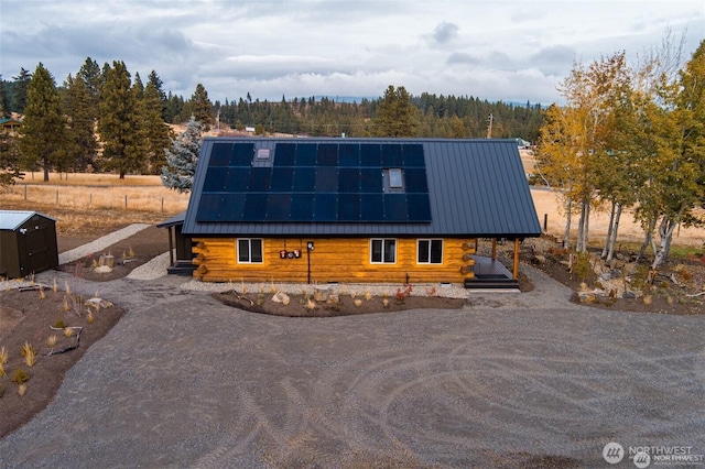 log home featuring log siding, metal roof, solar panels, and a wooded view
