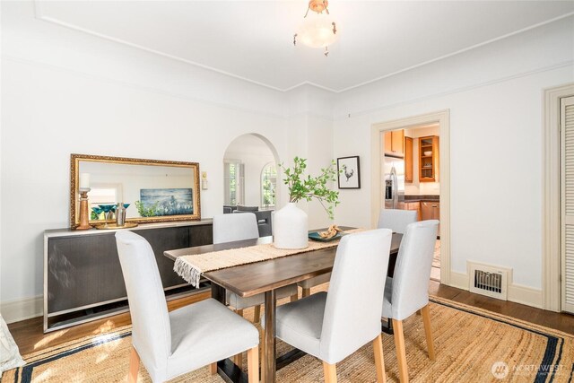 dining area with arched walkways, light wood finished floors, and baseboards