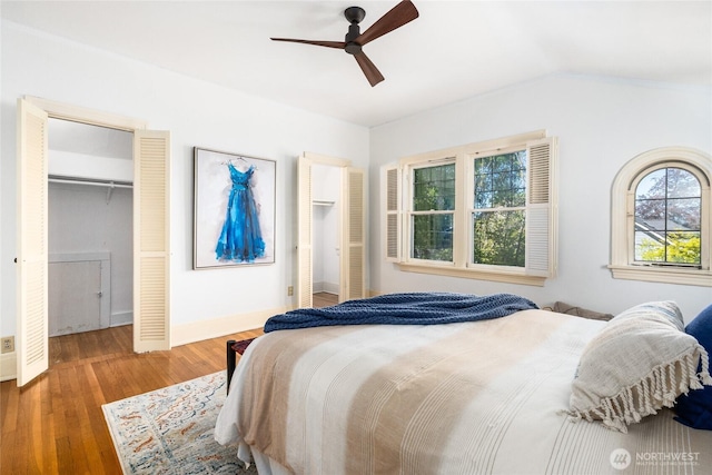 bedroom featuring wood finished floors, baseboards, ceiling fan, vaulted ceiling, and a spacious closet
