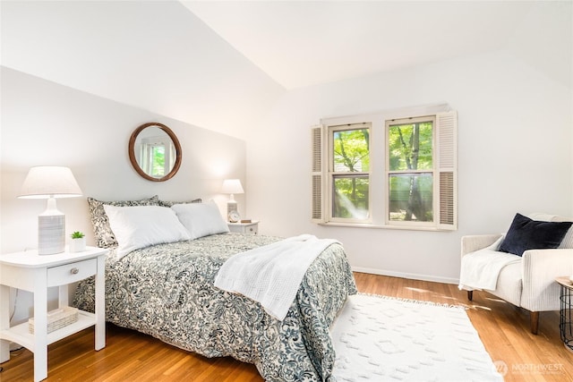 bedroom featuring wood finished floors, vaulted ceiling, and baseboards