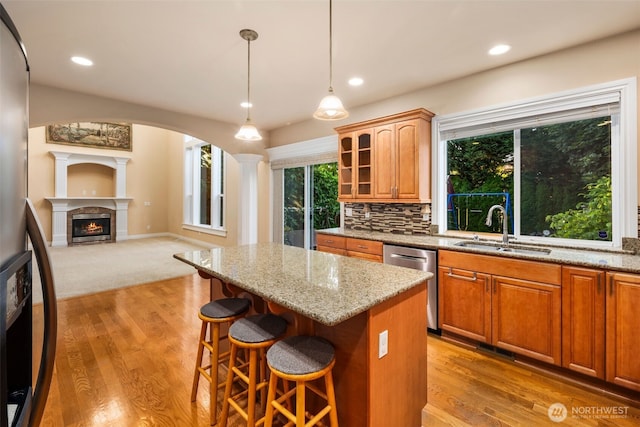 13106 SE 261st Pl, Kent, WA 98030 - kitchen with dishwasher, a kitchen island, light stone counters, a breakfast bar, and a lit fireplace