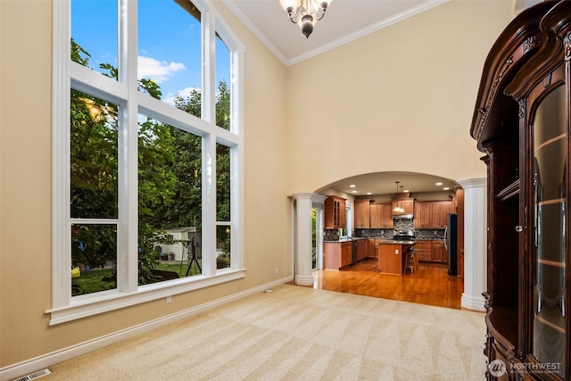13106 SE 261st Pl, Kent, WA 98030 - unfurnished living room with ornate columns, arched walkways, light colored carpet, crown molding, and a towering ceiling
