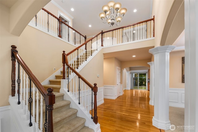 13106 SE 261st Pl, Kent, WA 98030 - staircase with arched walkways, a chandelier, a decorative wall, wood finished floors, and wainscoting