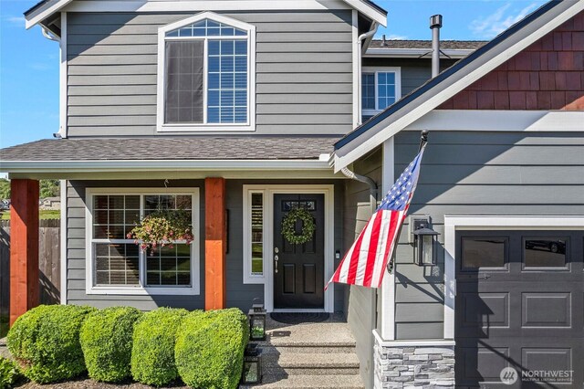 property entrance with fence and roof with shingles
