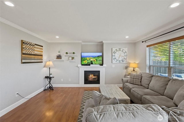 living room with wood finished floors, crown molding, baseboards, recessed lighting, and a glass covered fireplace