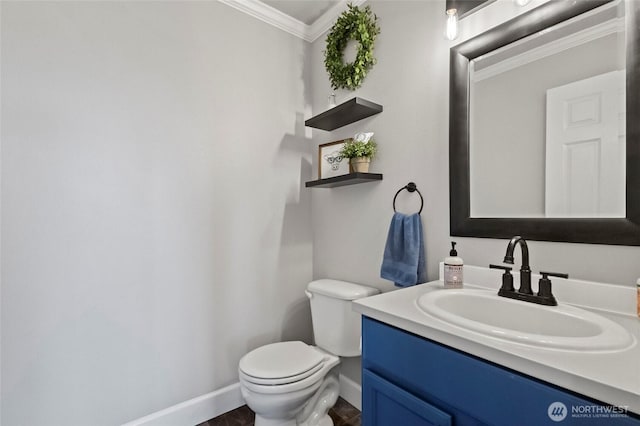 bathroom featuring crown molding, toilet, vanity, and baseboards