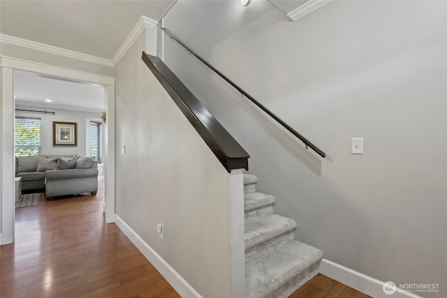 stairway featuring wood finished floors, baseboards, and ornamental molding