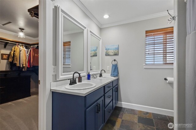 full bathroom with crown molding, baseboards, double vanity, and a walk in closet