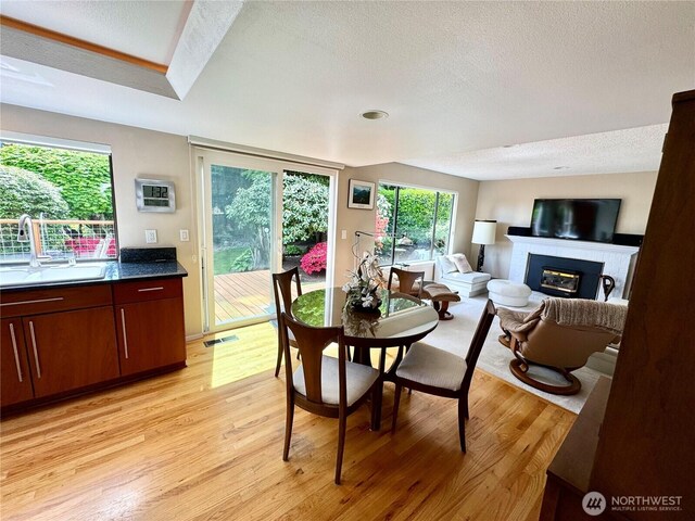 332 162nd Pl SE, Bothell, WA 98012 - dining area featuring a textured ceiling, a glass covered fireplace, light wood-style flooring, and healthy amount of natural light