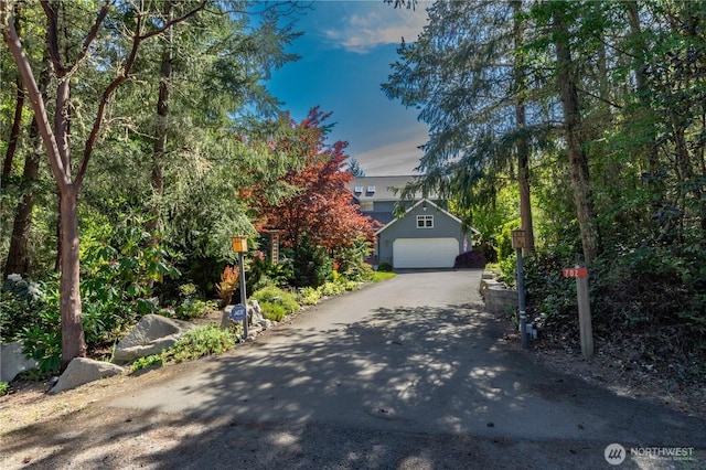 702 Woodland Dr, Port Townsend, WA 98368 - obstructed view of property featuring asphalt driveway, a garage, and an outdoor structure