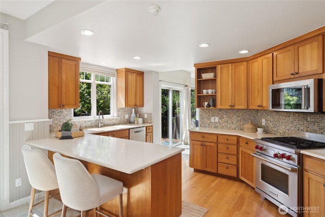 702 Woodland Dr, Port Townsend, WA 98368 - kitchen featuring appliances with stainless steel finishes, a sink, open shelves, a breakfast bar area, and light countertops