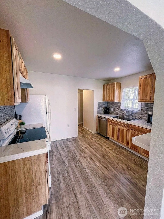 kitchen featuring stainless steel dishwasher, brown cabinets, a sink, light countertops, and decorative backsplash
