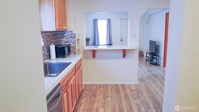 kitchen featuring dishwasher, light wood-style flooring, backsplash, and light countertops