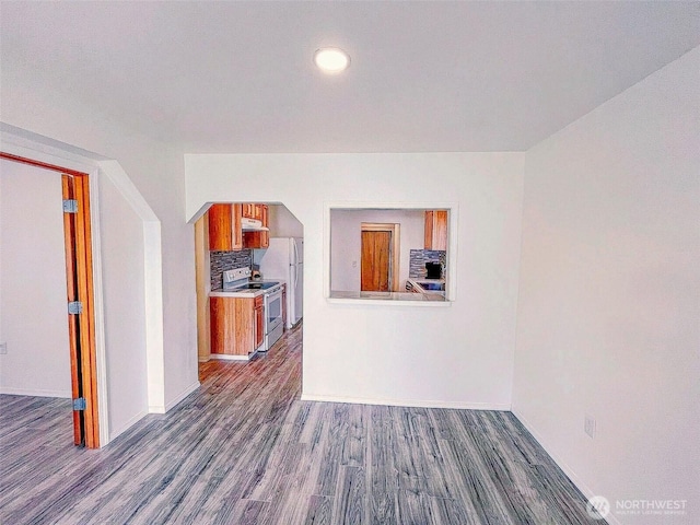 unfurnished living room with dark wood-style floors, arched walkways, baseboards, and recessed lighting