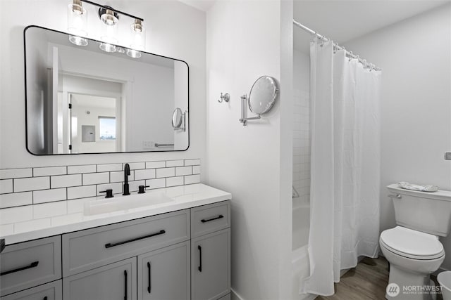 3121 W Hood Ave Unit E203, Kennewick, WA 99336 - bathroom featuring decorative backsplash, toilet, vanity, shower / bathtub combination with curtain, and wood finished floors