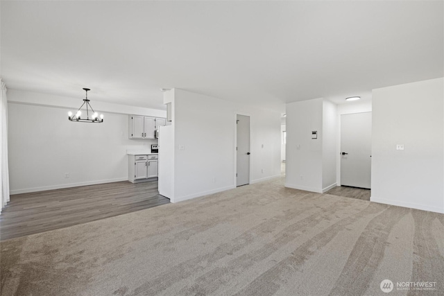 3121 W Hood Ave Unit E203, Kennewick, WA 99336 - unfurnished living room featuring a chandelier, light colored carpet, and baseboards