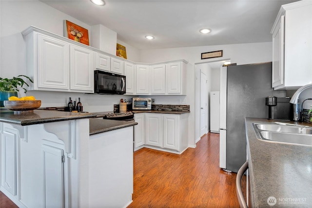 4805 Cushman Rd NE Unit 61, Olympia, WA 98506 - kitchen with white cabinets, a sink, light wood-style floors, dark countertops, and recessed lighting