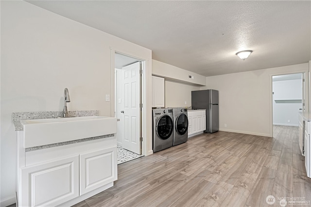 30521 NE 147th Ct, Battle Ground, WA 98604 - washroom featuring cabinet space, independent washer and dryer, light wood-type flooring, baseboards, and a textured ceiling