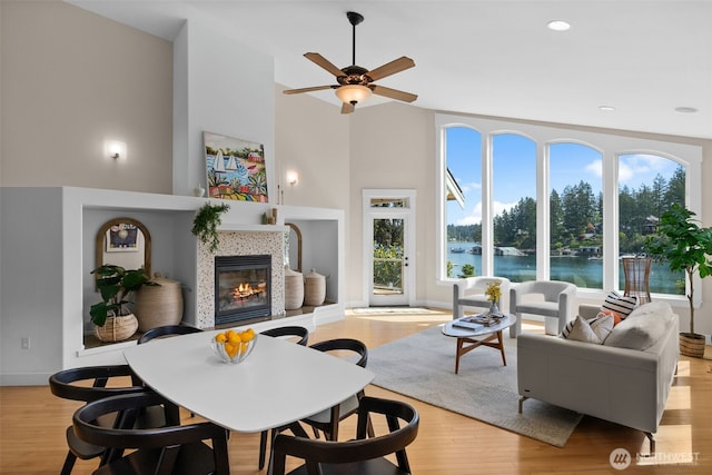 257 3rd Ave, Fox Island, WA 98333 - living room featuring a fireplace, plenty of natural light, light wood finished floors, a ceiling fan, and a towering ceiling