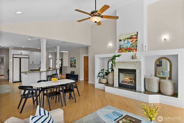 257 3rd Ave, Fox Island, WA 98333 - living room featuring decorative columns, high vaulted ceiling, a fireplace, ceiling fan, and light wood-style floors