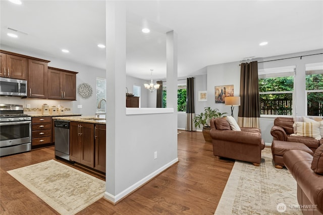 kitchen featuring appliances with stainless steel finishes, a sink, open floor plan, a chandelier, and plenty of natural light