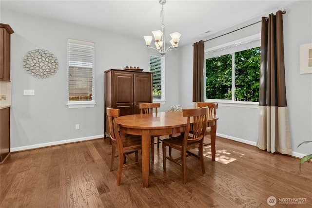 dining area featuring a chandelier, wood finished floors, and baseboards