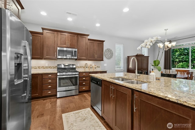kitchen featuring appliances with stainless steel finishes, a sink, a chandelier, dark wood finished floors, and hanging light fixtures