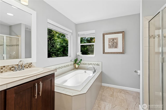 full bathroom featuring a stall shower, vanity, a bath, and baseboards