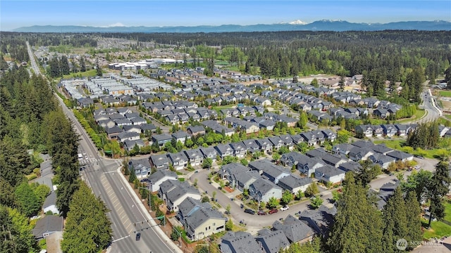 view of property location with a forest, nearby suburban area, and a mountain backdrop