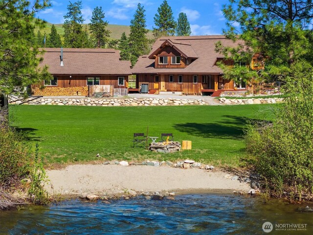 back of house with a yard, an outdoor fire pit, and a water view
