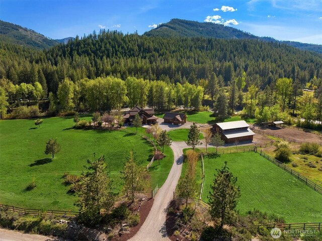 view of rural area with a heavily wooded area and a mountainous background
