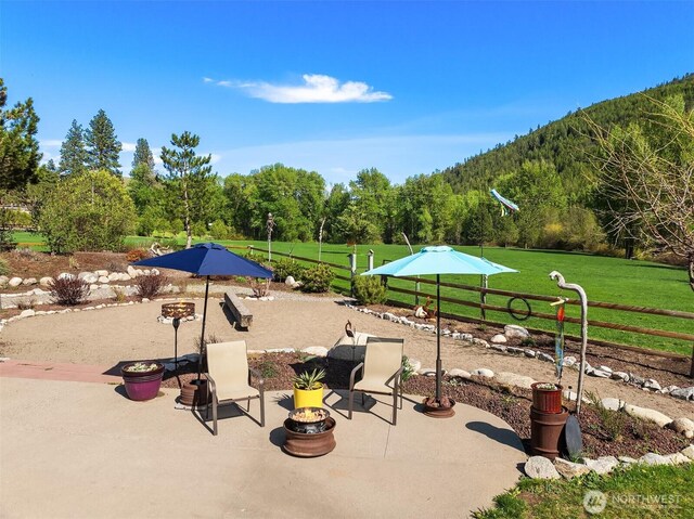 view of property's community featuring a patio area, an outdoor fire pit, a mountain view, and a forest view